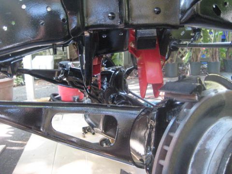 1988 Ford Bronco - Close-up view of a vehicle's undercarriage, showing the frame and suspension system with a red jack.