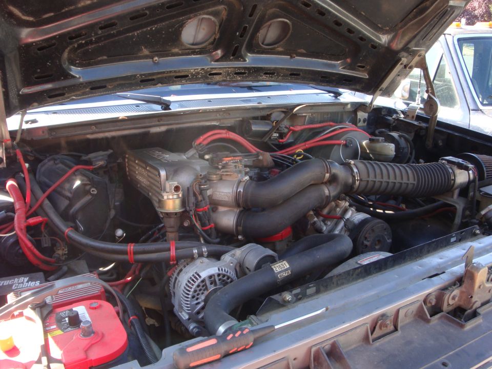 Ford truck engine bay with V8, red plug wires and intake piping
