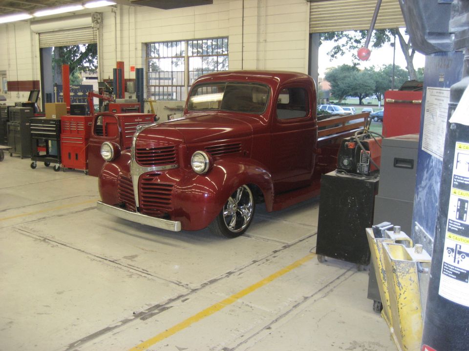 Red pickup truck with chrome wheels in a garage