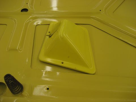 1978 Ford Bronco - Close-up of a yellow painted metal surface with a yellow plastic vent and a black spring visible.