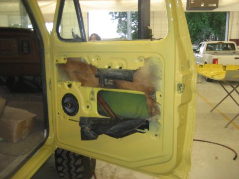 1978 Ford Bronco - Interior of a yellow car door showing speaker and wiring, with a white pickup truck visible in the background.