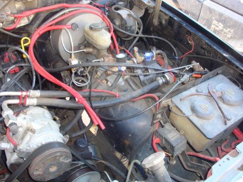 1989 Ford Bronco - The engine bay shows various components including the AC compressor and brake booster, with prominent red wiring throughout.