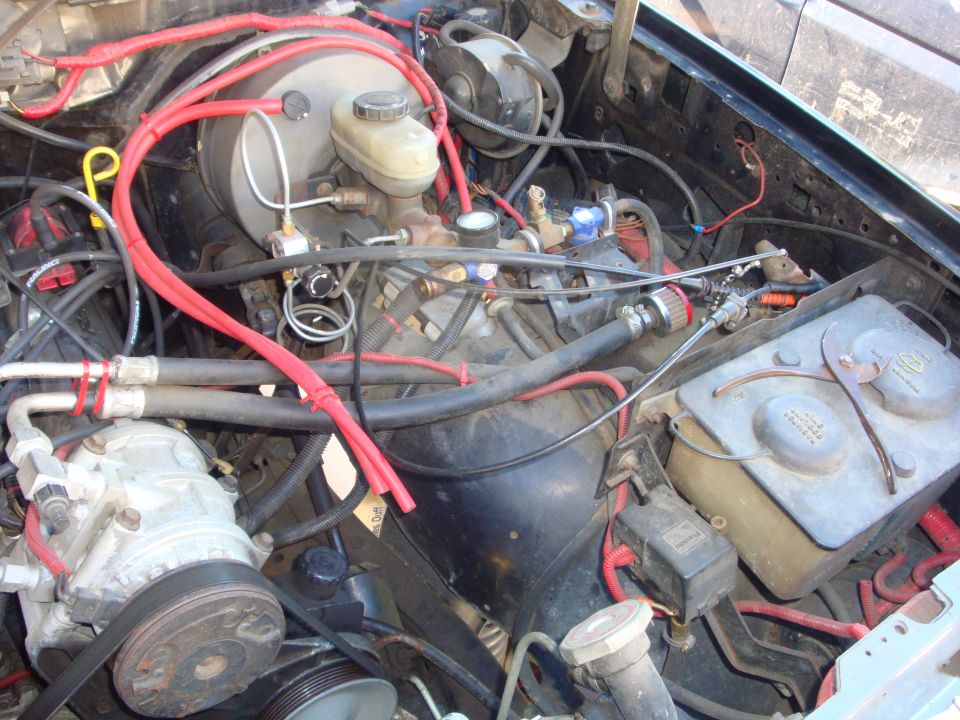 Ford truck engine bay mid-swap with red plug wires, A/C compressor and brake booster