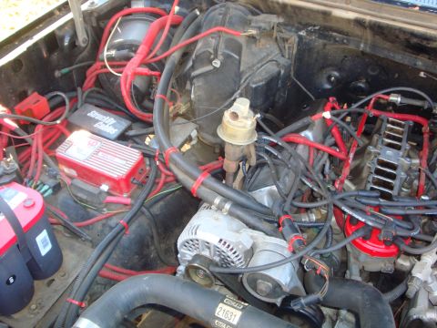 1989 Ford Bronco - Close-up view of a vehicle's engine bay, prominent red wiring and various engine components.