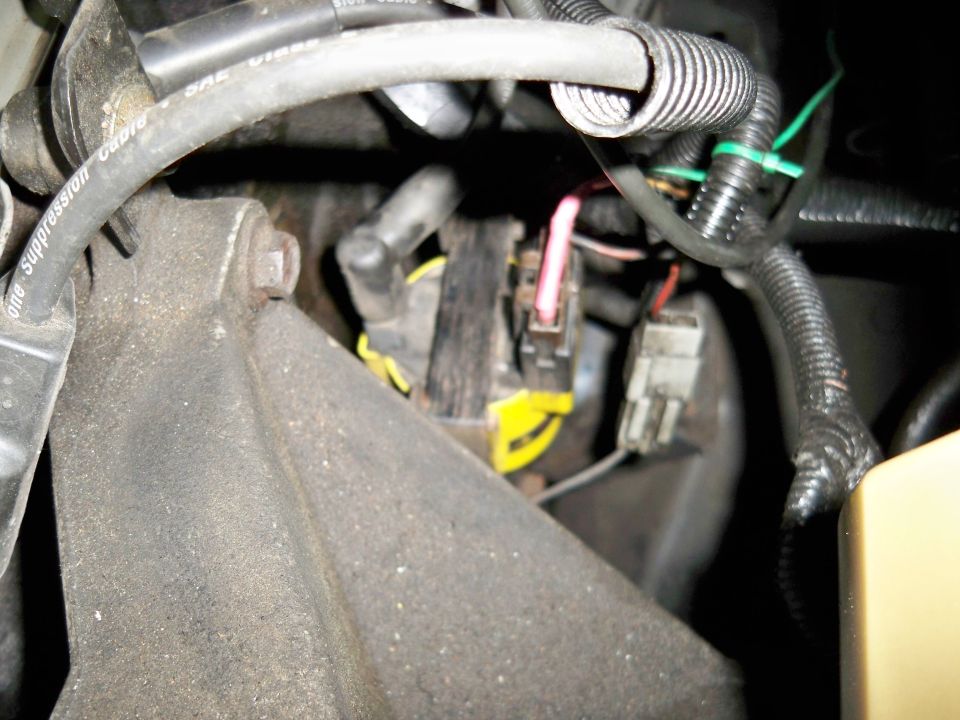 Close-up of engine wiring harness and connectors, some yellow and pink wires visible