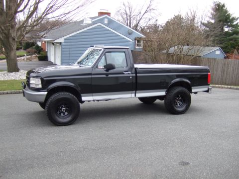 1995 Ford F-150 - A black 1992 Ford F-150 pickup truck is shown from the side, parked in a driveway.