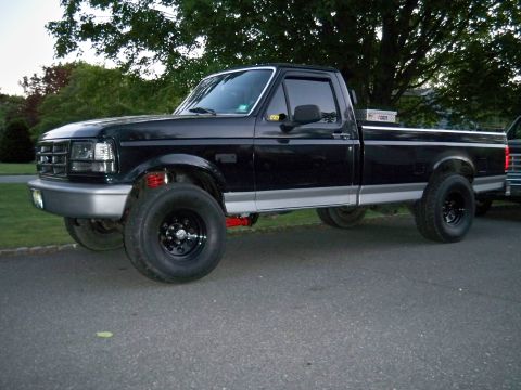 1995 Ford F-150 - This black Ford F-150 pickup truck features a lifted suspension and custom wheels.