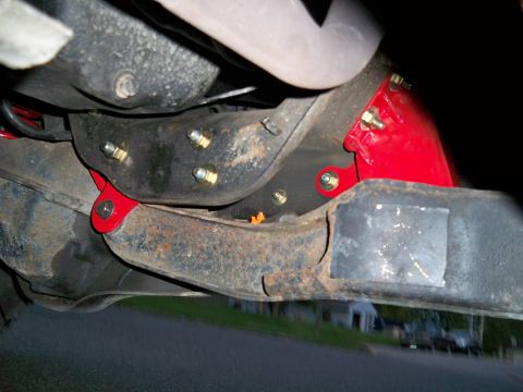 1995 Ford F-150 - Close-up view of red aftermarket suspension components installed on the underbody of a truck.