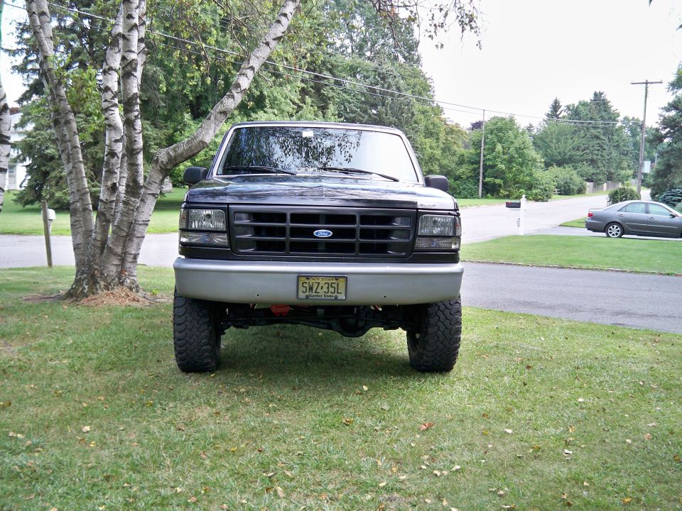 Black Ford F-150 truck, front view, parked on grass with trees and a mailbox. License plate SWZ-35L