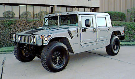 1998 Ford Crown Victoria - A silver Hummer H1 is shown from a 3/4 front angle, parked on a paved surface in front of a building.