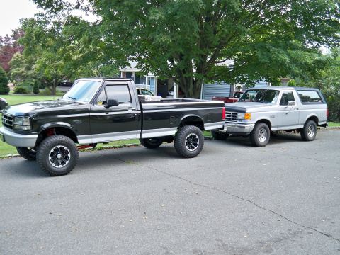 1995 Ford F-150 - Two Ford trucks, an F-150 and a Bronco, are parked side-by-side on a paved driveway.