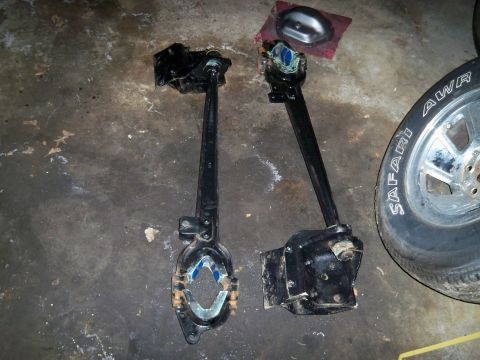 1995 Ford F-150 - Two suspension components and a tire are laid out on a concrete floor.
