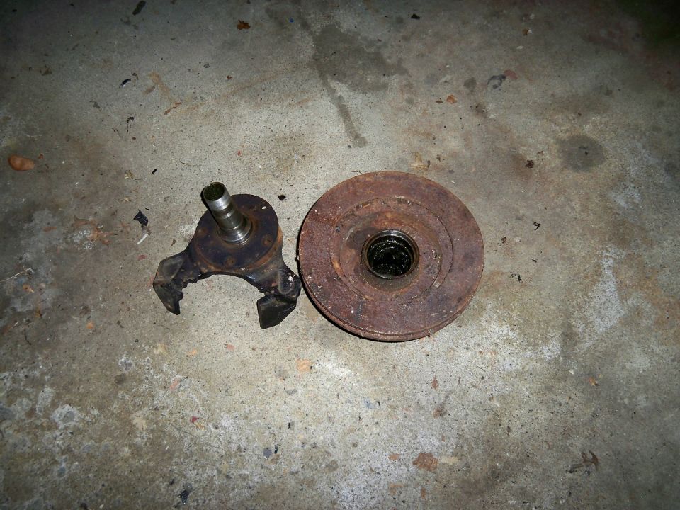 Rusty brake rotor and spindle assembly on concrete floor