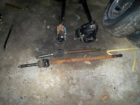 1995 Ford F-150 - Various automotive parts, including driveshafts and suspension components, laid out on a concrete surface.