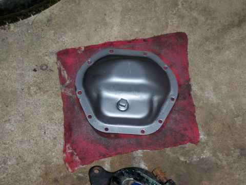 1995 Ford F-150 - A differential cover rests on a red shop rag on a concrete floor, with a website address visible in the lower right corner.