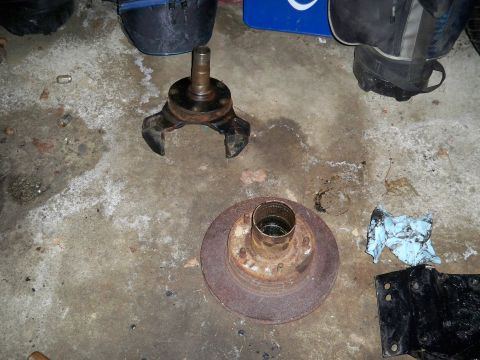 1995 Ford F-150 - A wheel hub assembly and a rusty brake rotor are shown on a concrete floor, possibly for a vehicle repair or rebuild.