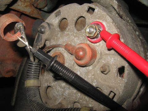 1981 Ford Bronco - Close-up of an alternator with test leads connected, indicating a diagnostic procedure.