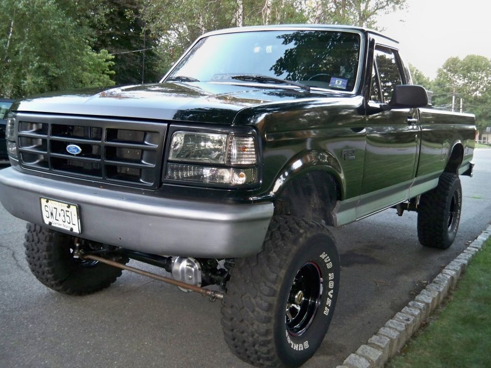 Lifted 1995 Ford F-150 pickup truck, dark green, with large tires and aftermarket wheels