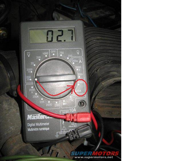 Digital multimeter with red and black leads connected, displaying 02.7