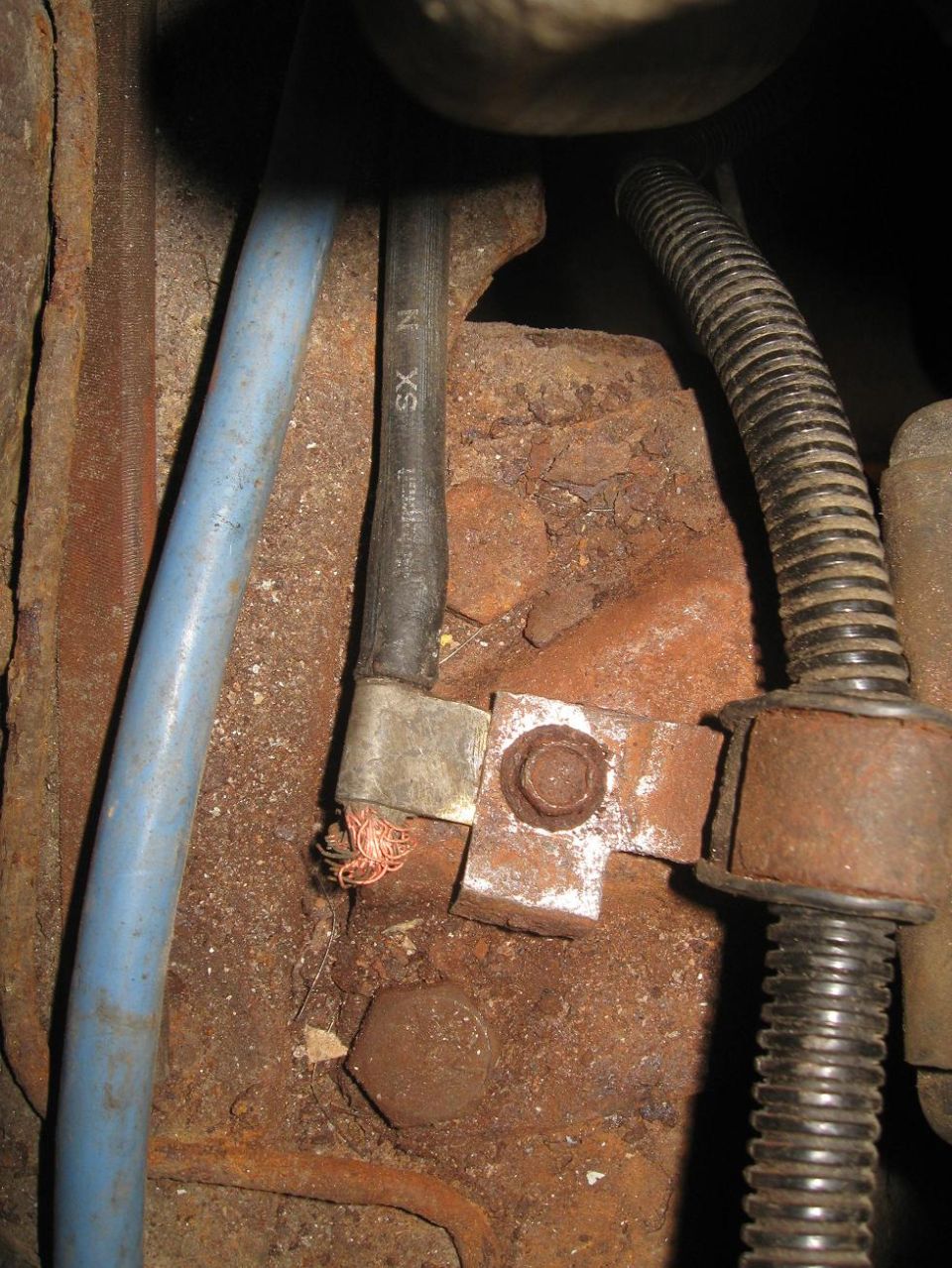 Close-up of engine bay wiring and rusted metal components