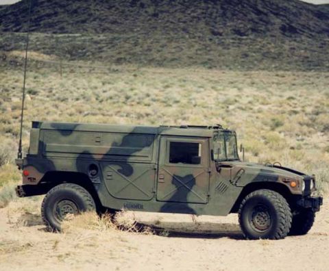 1998 Ford Crown Victoria - A camouflaged Humvee sits in a dry, desert environment, with a mountain range in the background.