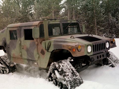 1998 Ford Crown Victoria - Military Humvee with tracks navigates a snow-covered terrain.