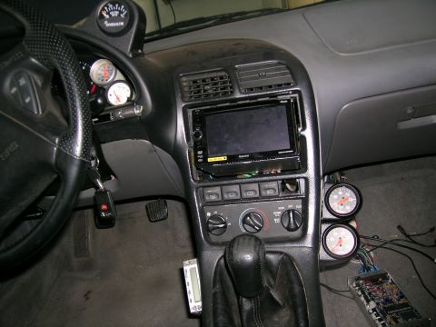 1995 Ford Probe - Customized car interior features several aftermarket gauges and a modern stereo system, suggesting performance modifications.