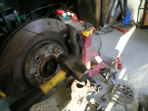 1995 Ford Probe - Mechanic works on a car's brake system, with tools and parts scattered around.