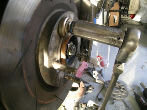 1995 Ford Probe - Close-up of a wheel hub assembly with a torque wrench being used on the lug nuts.