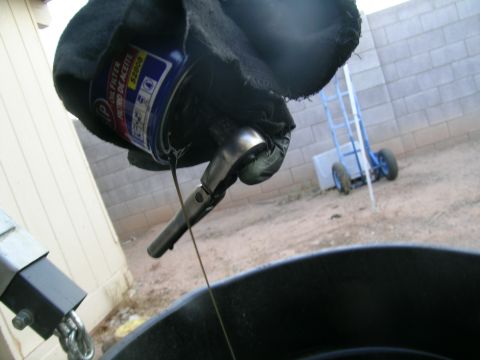 1995 Ford Probe - Removing an oil filter with a wrench, with oil dripping into a pan below.