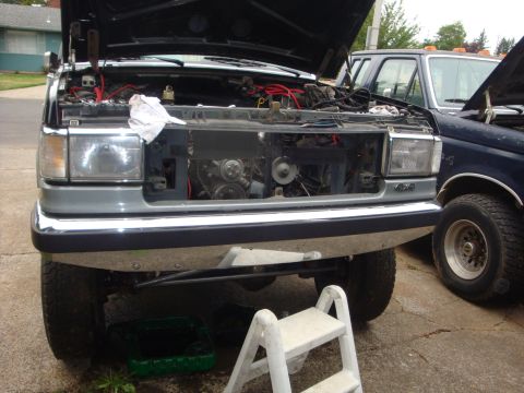 1989 Ford Bronco - Front view of a 1989 Ford Bronco with its hood open, revealing the engine compartment, parked next to another truck.