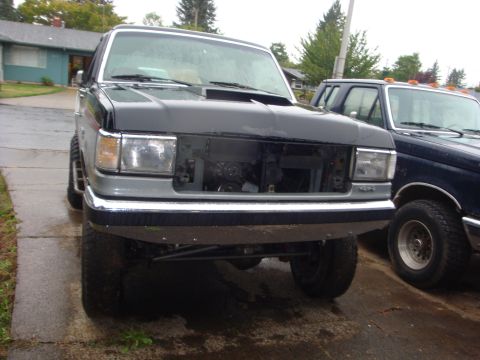 1989 Ford Bronco - This pickup truck, likely a 1987-1991 Ford F-Series, is shown from the front with its grille removed, revealing the engine bay.
