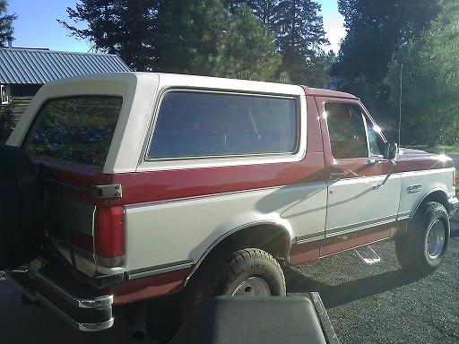 Red and white Ford Bronco parked outside a building