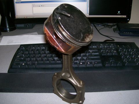 1995 Ford Probe - A close-up of a piston and connecting rod assembly is shown on a desk.