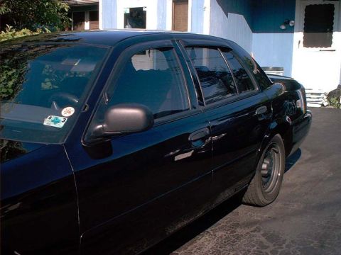 2000 Ford Crown Victoria - Side view of a black sedan with tinted windows and aftermarket wheels parked in a driveway.