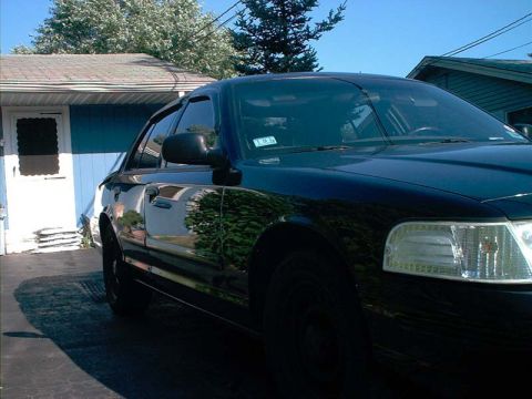 2000 Ford Crown Victoria - A black 2000 Ford Crown Victoria is parked in front of a house.