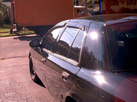 2000 Ford Crown Victoria - A black 2000 Ford Crown Victoria is seen from the 3q-front angle, window visors and a sun glare on the paint.