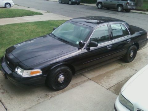 2003 Ford Crown Victoria - A black 2003 Ford Crown Victoria sedan is parked on a concrete driveway.