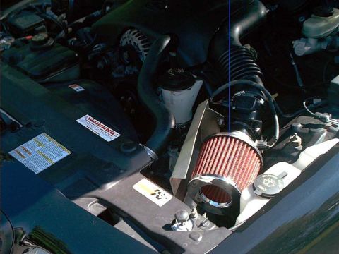 2000 Ford Crown Victoria - Engine bay detail of a cold-air intake conversion: a red conical cotton-gauze filter on a chrome coupler feeds the mass air sensor and corr…