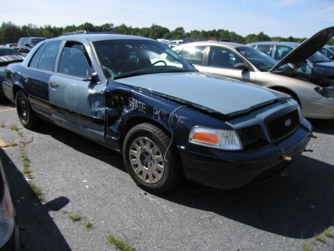 1991 Ford LTD Crown Victoria - This damaged two-tone sedan, possibly a former police vehicle, is seen in a lot with other cars.