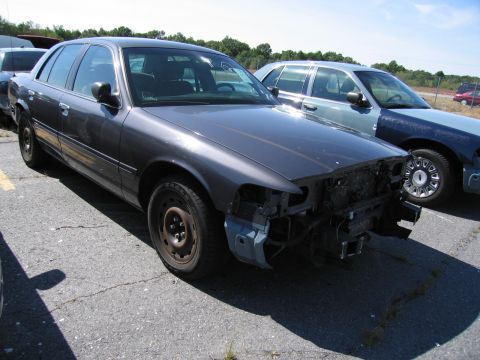 1991 Ford LTD Crown Victoria - Two Ford Crown Victorias parked outside, one with significant front-end damage.