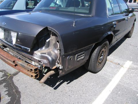 1991 Ford LTD Crown Victoria - Rear view of a Ford Crown Victoria missing its bumper, revealing structural components and exhaust.