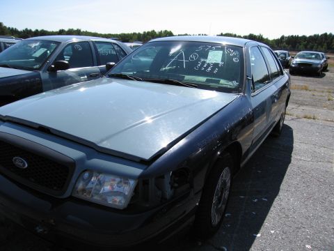 1991 Ford LTD Crown Victoria - Two Ford Crown Victorias are parked in a lot, one with visible damage to its front end.