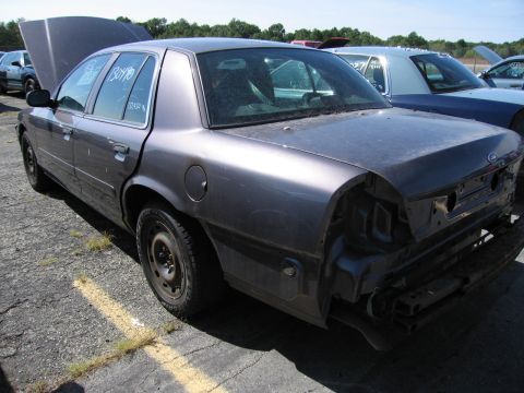1991 Ford LTD Crown Victoria - Rear view of a gray Ford Crown Victoria, missing its bumper, with hood up. Another vehicle is visible.