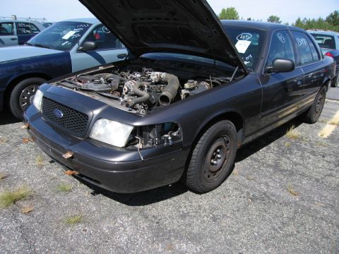 1991 Ford LTD Crown Victoria - This dark sedan, likely a Ford Crown Victoria from the early 2000s, is parked with its hood open, revealing the engine compartment and miss…