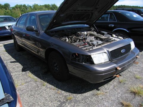 1991 Ford LTD Crown Victoria - A dark gray Ford Crown Victoria sits in a lot with its hood open, revealing the engine compartment.