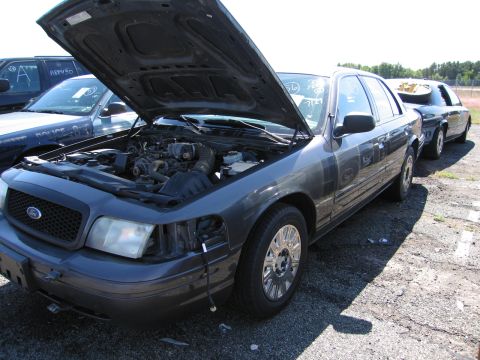 1991 Ford LTD Crown Victoria - A dark gray Ford Crown Victoria sedan is parked with its hood open, revealing the engine compartment.