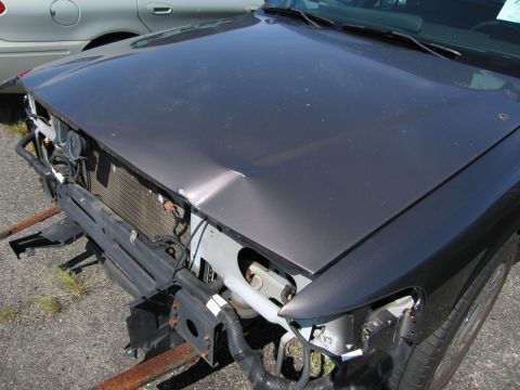 1991 Ford LTD Crown Victoria - The front of a dark gray sedan shows significant damage to the hood and bumper area, with the radiator exposed.