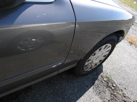 1991 Ford LTD Crown Victoria - Close-up of a car's side door and wheel, showing minor damage.