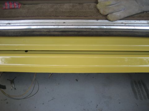 1978 Ford Bronco - A close-up view of the interior door sill of a vehicle, showing yellow paint and carpeted flooring.